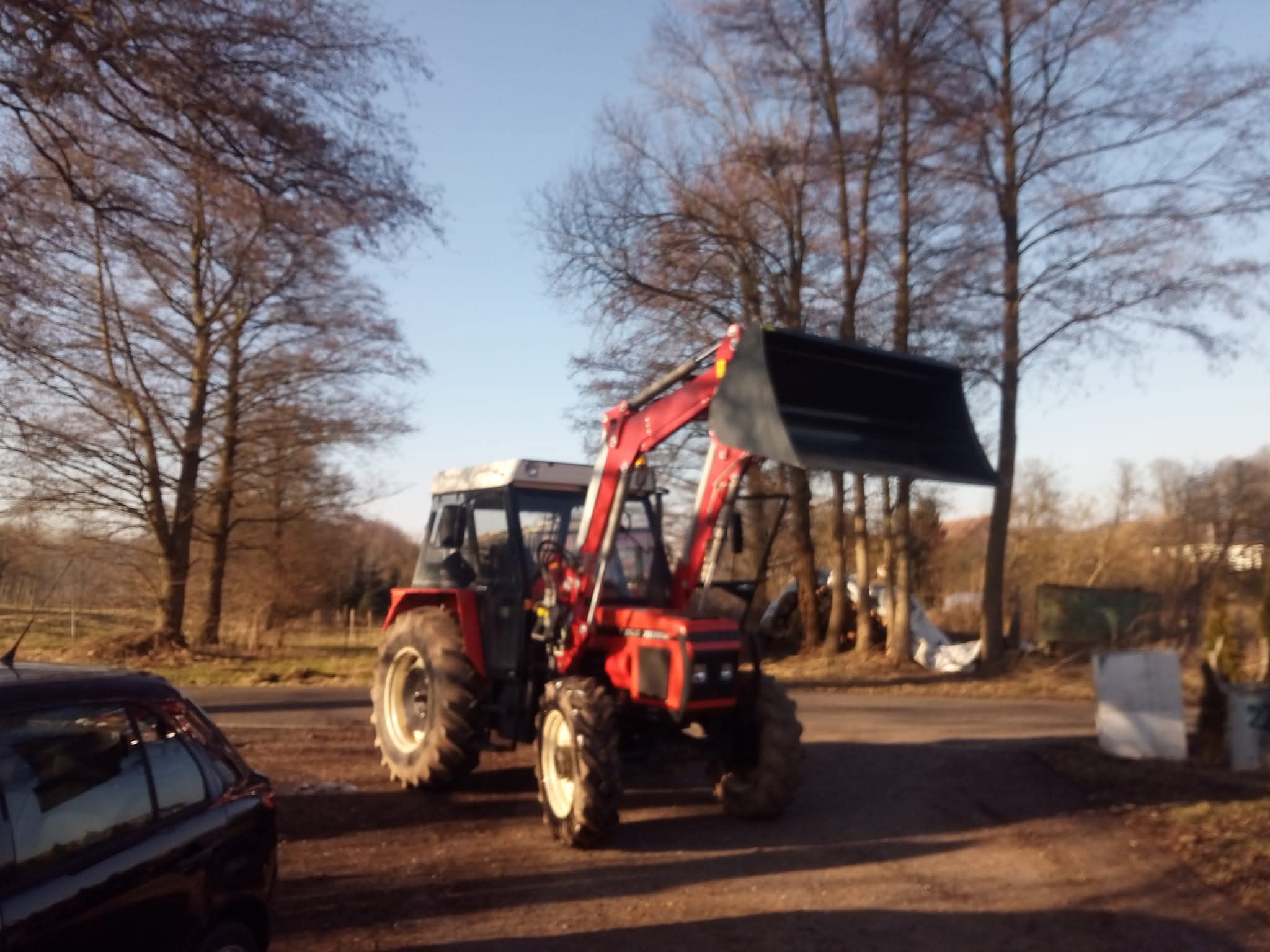 Červený traktor s čelním nakladačem na dvoře